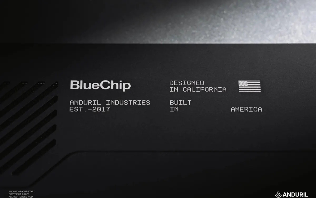 Тёмная крышка ноутбука BlueChip с надписью «Designed in California, Built in America» и флагом США