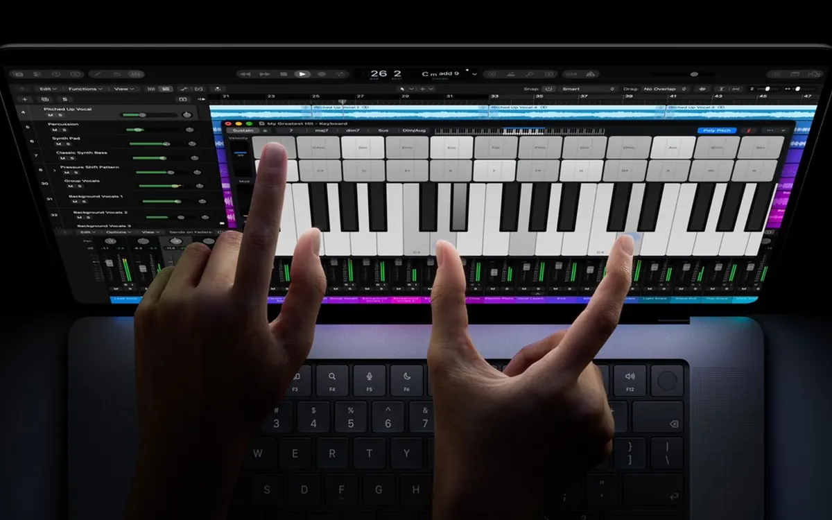 Руки играют на экранной клавиатуре пианино в Logic Pro на сенсорном дисплее MacBook Pro с PROLED XDR