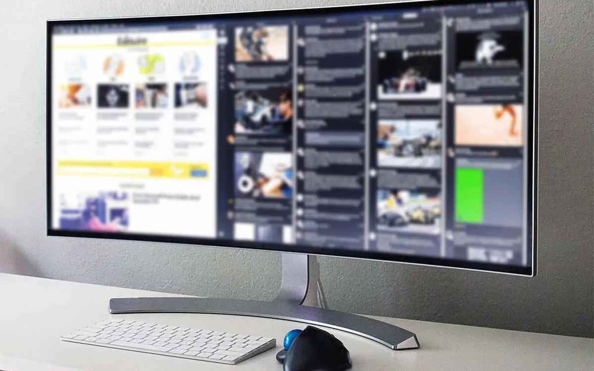 A curved ultrawide monitor on a white desk with a keyboard and a trackball mouse (illustrative photo)