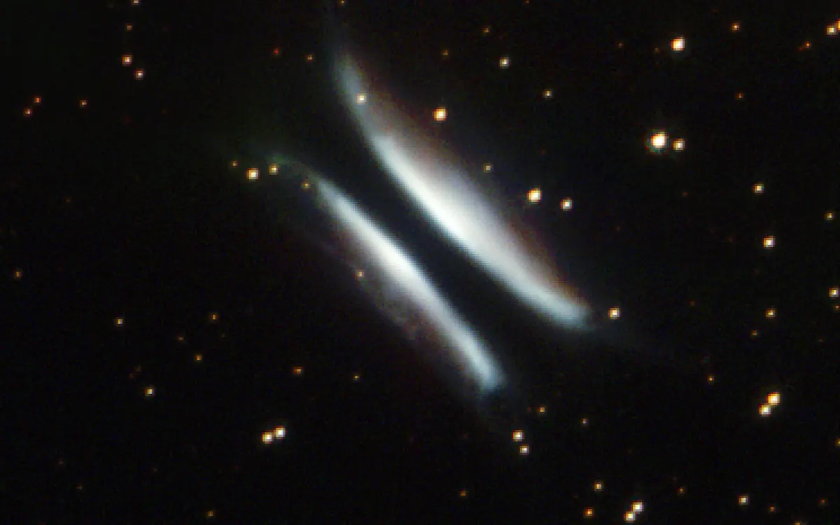 Hubble's 2002 image of Gomez's Hamburger: two bright, bun-shaped lobes of lit-up dust split by a dark lane, against a field of stars