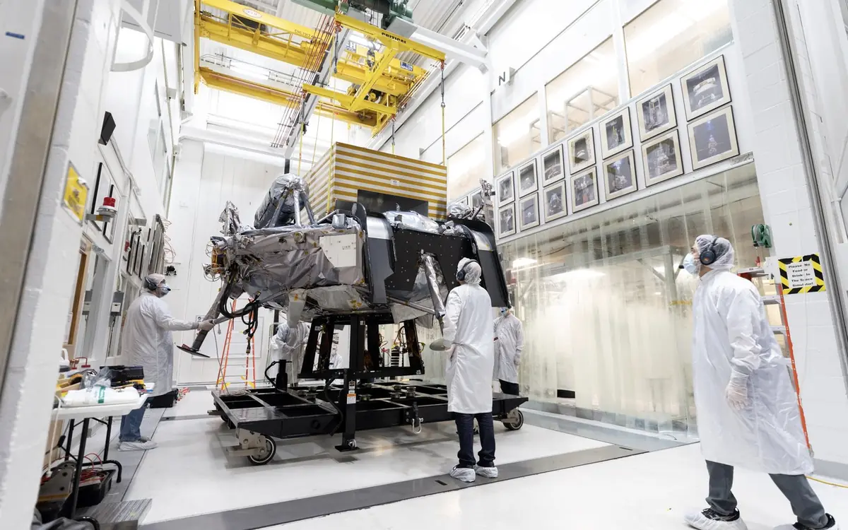 Engineers in clean-room suits move the Griffin-1 lunar lander through a JPL hallway to the 25-Foot Space Simulator