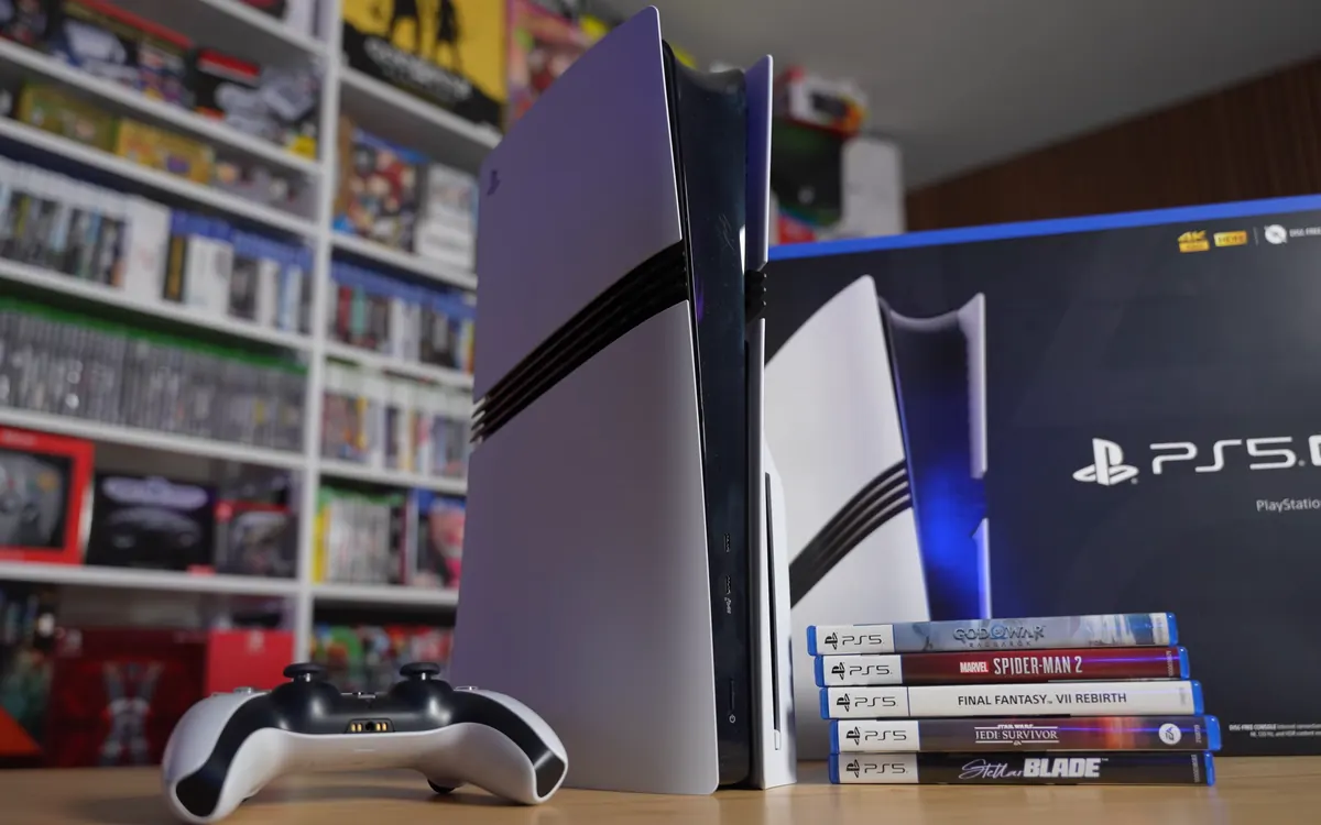 Белая консоль PlayStation 5 Pro рядом с коробкой, геймпадом DualSense и дисками с играми для PS5 (иллюстративное фото)