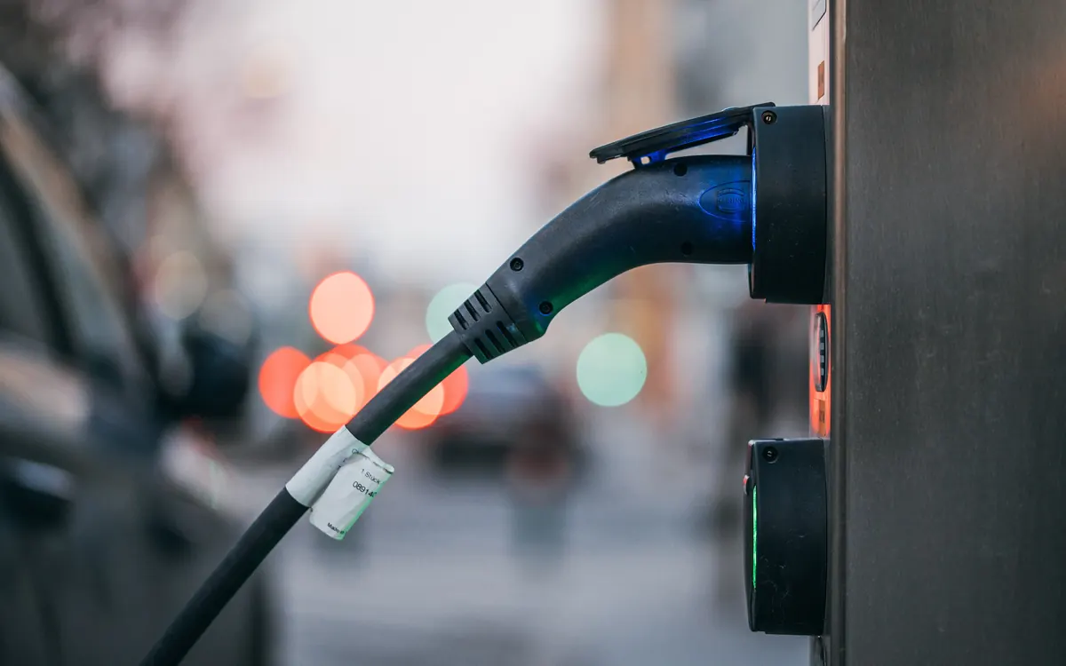 Close-up of a charging cable plugged into a public electric car charging station on a city street (illustrative photo)