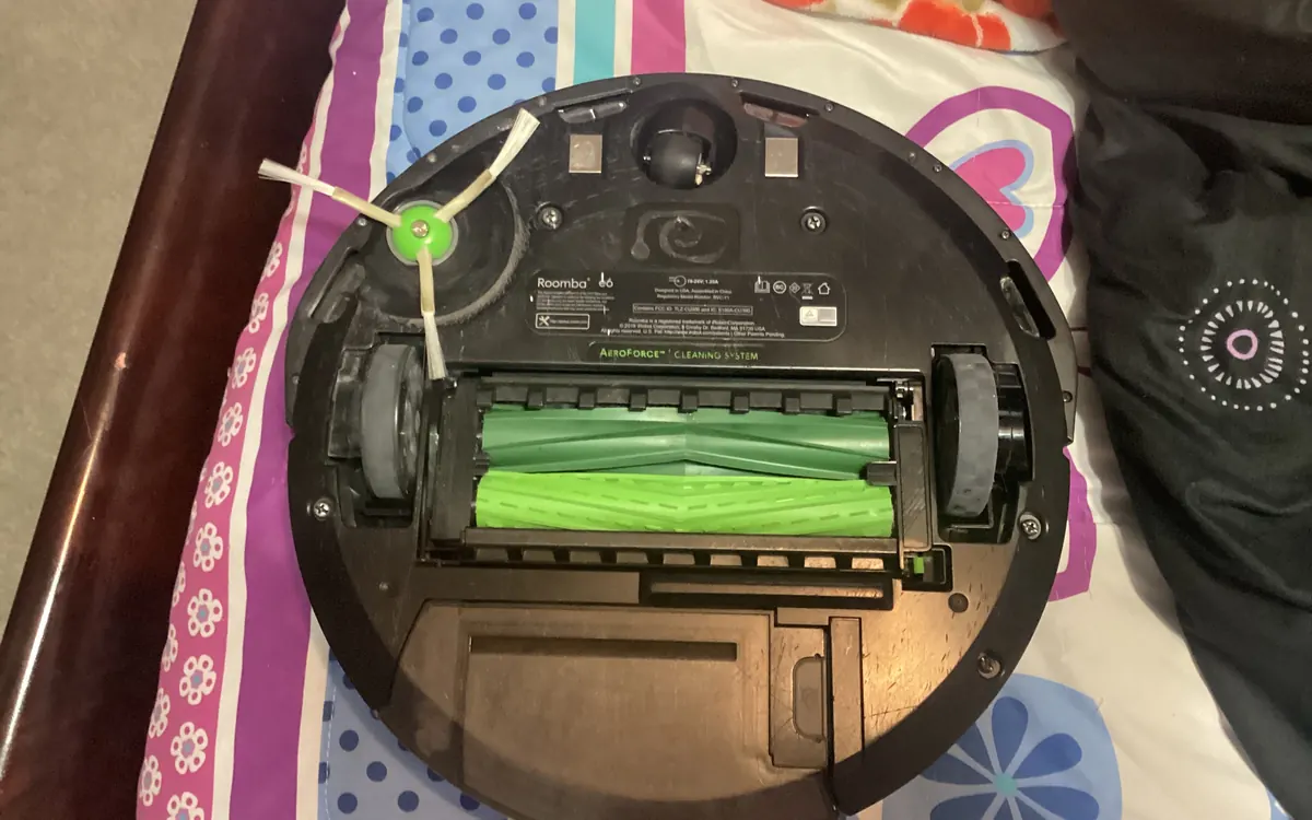 Нижня частина iRobot Roomba e6: зелені гумові основні щітки, бічна щітка й колеса (ілюстративне фото)