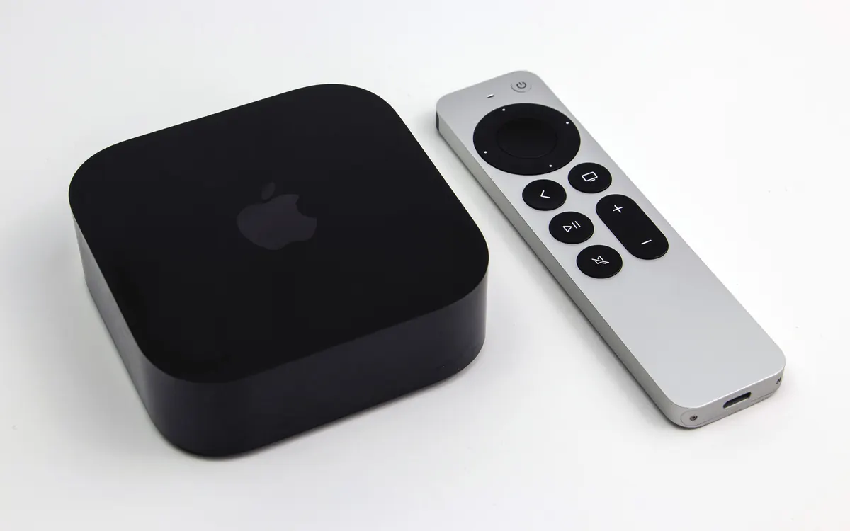 Чорна приставка Apple TV 4K і срібний пульт Siri Remote на білій поверхні (ілюстративне фото)