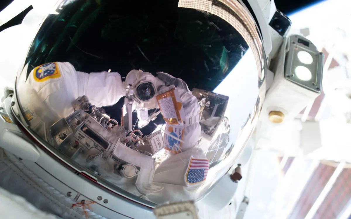 Селфи астронавта NASA Анила Менона в открытом космосе 25 августа 2026 года: камера отражается в визоре шлема