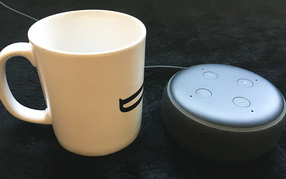 Amazon Echo Dot smart speaker next to a coffee mug