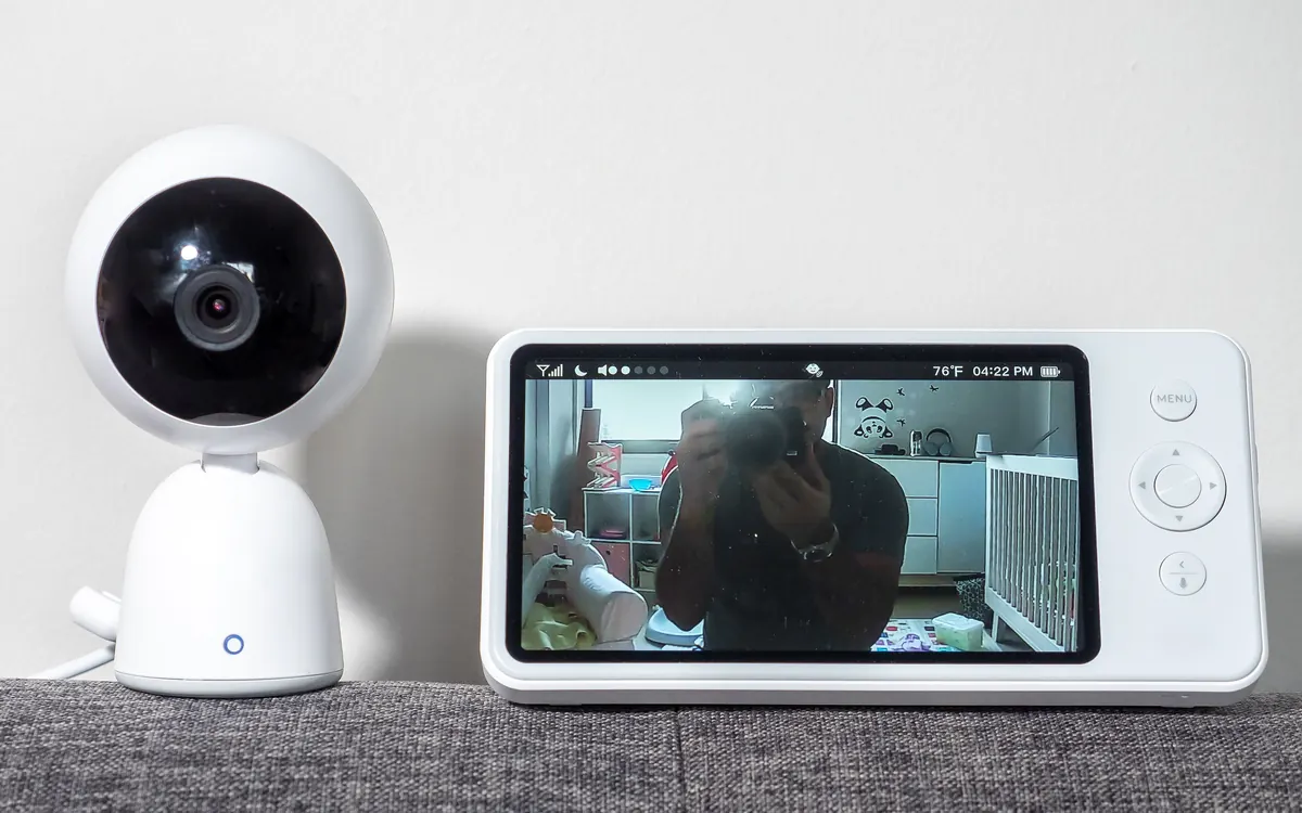 Video baby monitor: a white round camera next to a parent display showing a nursery (illustrative photo)
