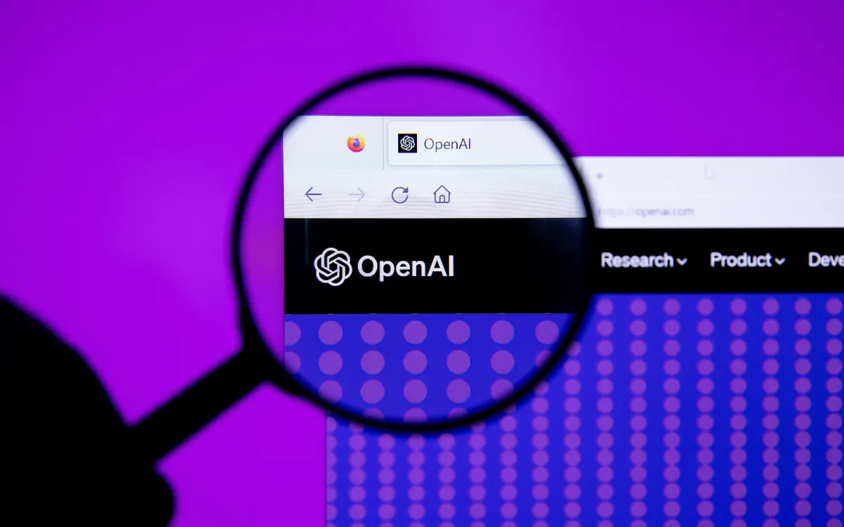 The OpenAI logo on a screen seen through a magnifying glass (illustrative photo)
