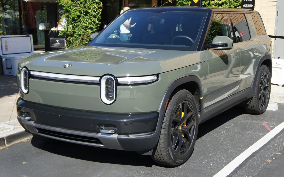A green Rivian R2 electric SUV parked on a city street