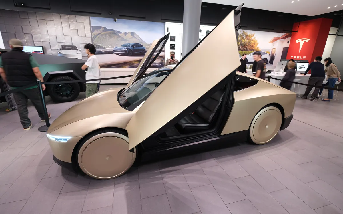 A gold Tesla Cybercab two-seater with its butterfly doors open, on display at Santana Row