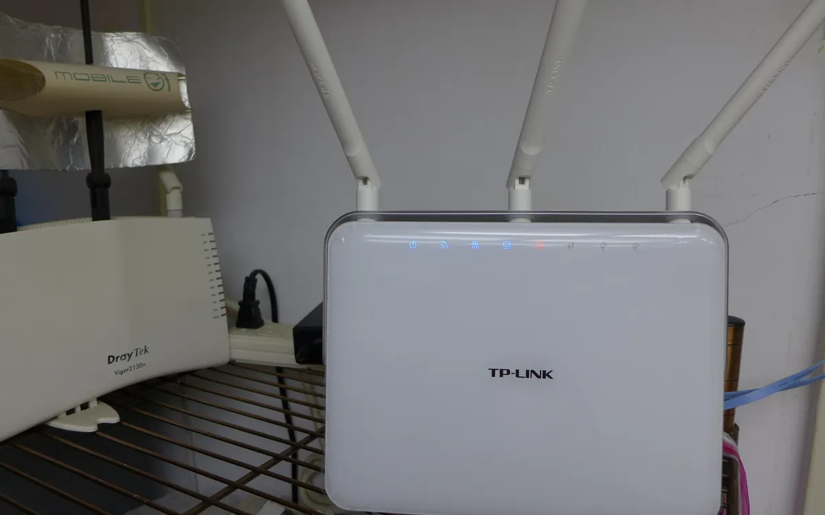 A white TP-Link Archer C9 Wi-Fi router with three antennas on a home shelf (illustrative photo of an older model)