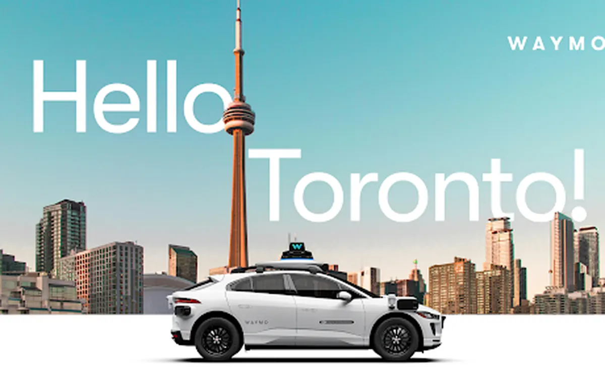 Waymo promotional image: a Waymo Jaguar robotaxi in front of the Toronto skyline and CN Tower